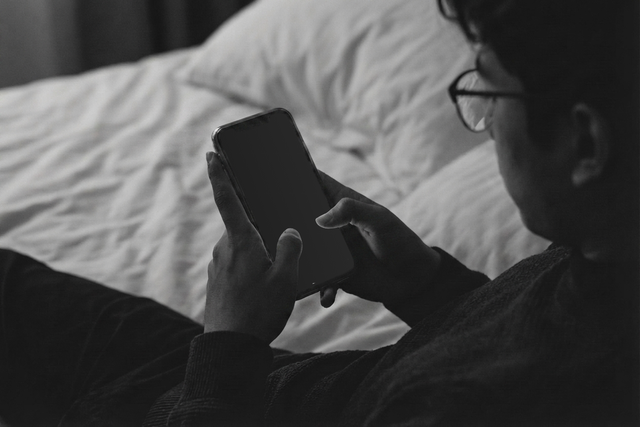Man in bed looking at a blank phone screen